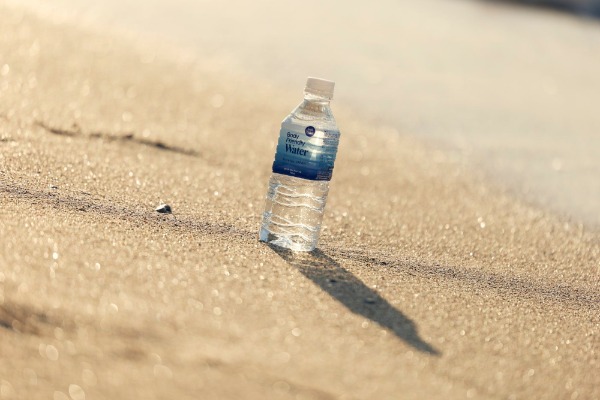 砂浜に置かれたBody Friendly Waterのボトル
