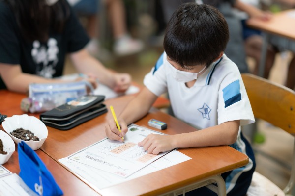 コーヒークイズの回答用紙に記入する小学生