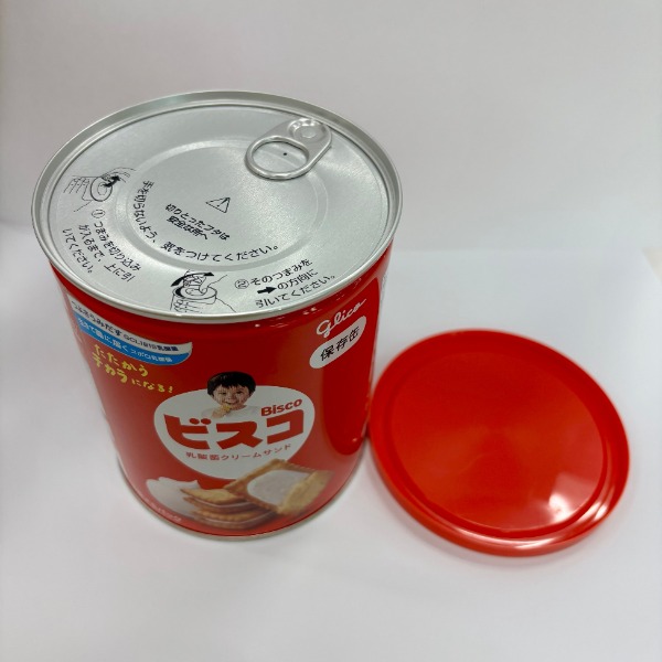 ビスコ保存缶の赤いふたに手紙を入れる様子